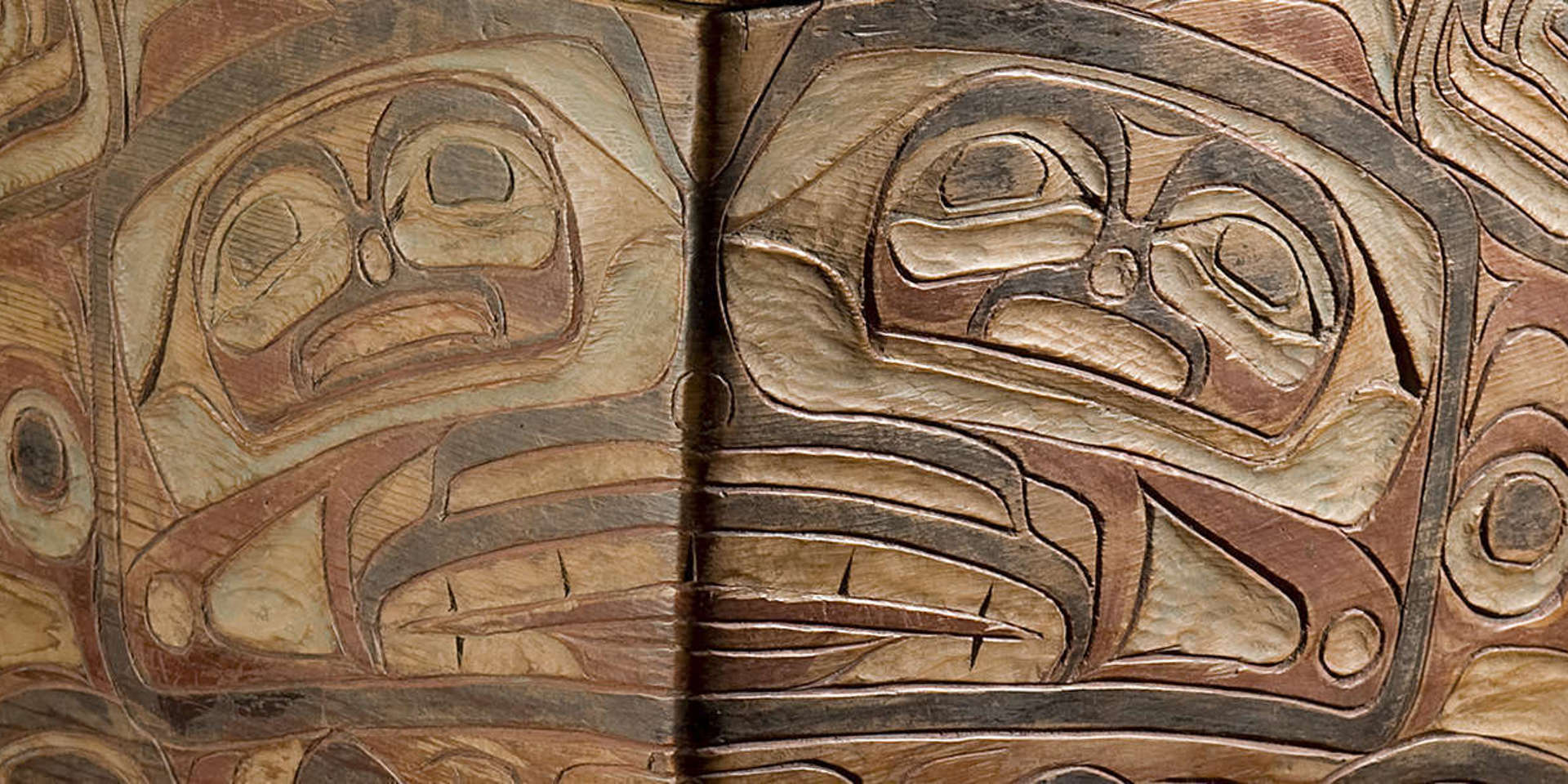 Close up of a Northwest Coast Native American carved wooden box with faded red and black paint