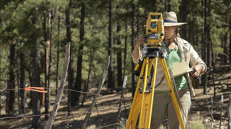 Three people using tools to excavate a paleontological site