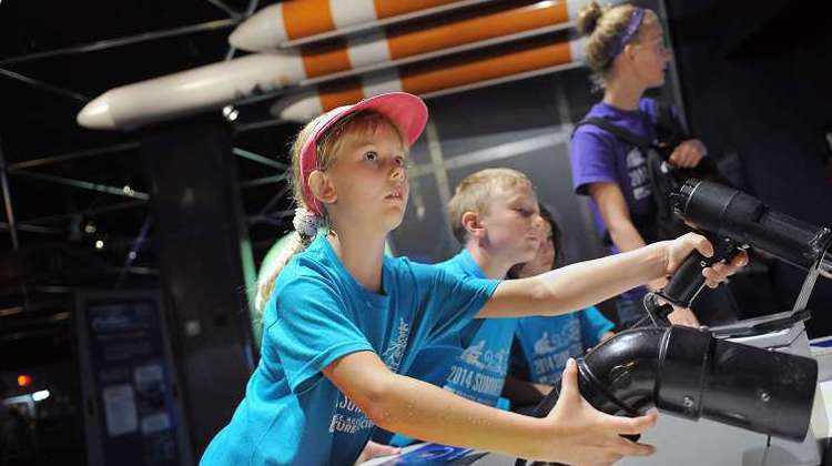 Children in blue t-shirts engage with an interactive display in Space Odyssey