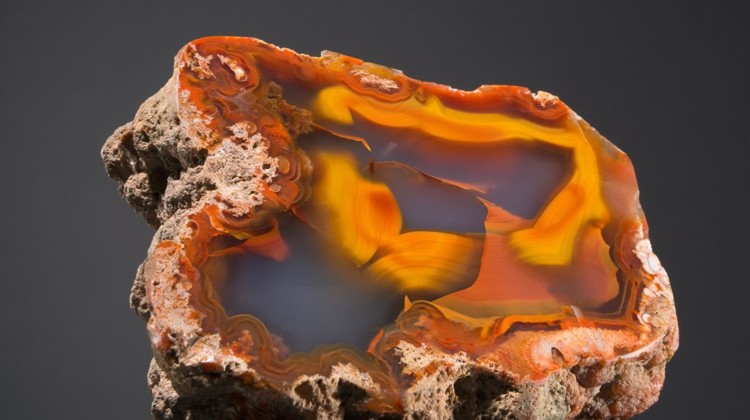 A rock is cut, displaying vibrant oranges and greys.