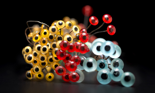 bunches of glass eyes from our taxidermy collection in bright colors of teal, red and yellow on a black background