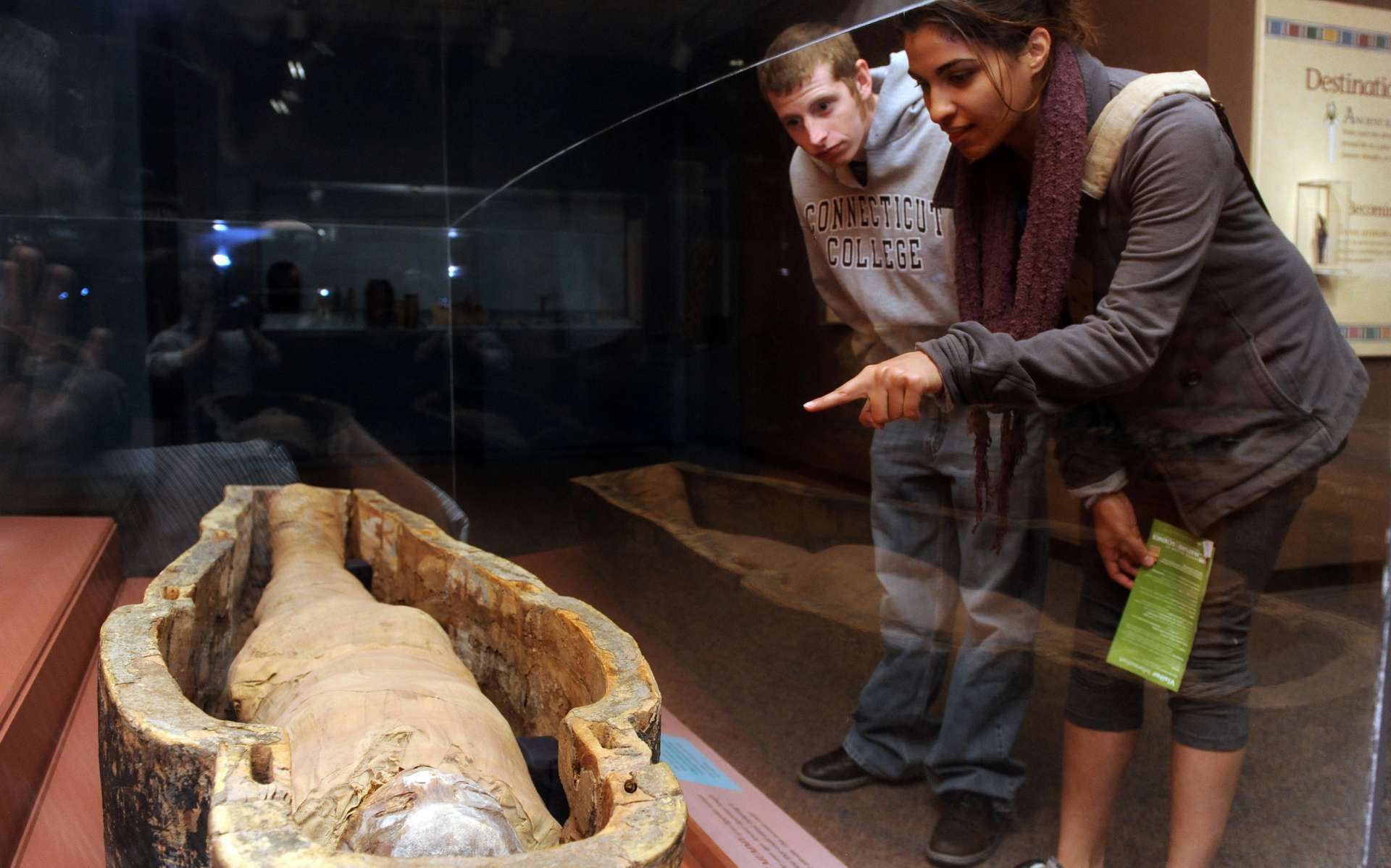 Two guests looking at an Egyptian mummy in a coffin