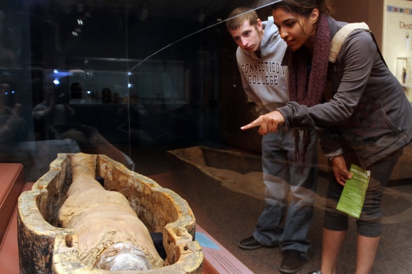 Two guests looking at an Egyptian mummy in a coffin