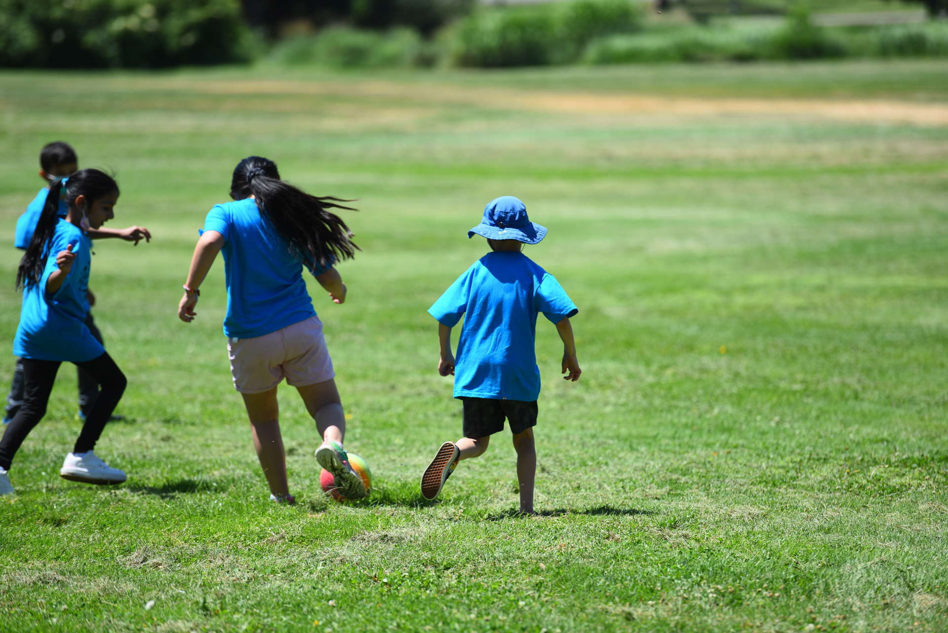 Four children run in City Park playing a game of soccer