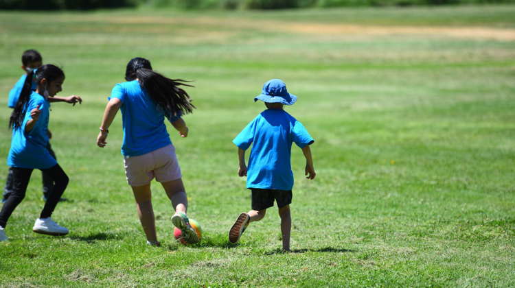 Four children run in City Park playing a game of soccer