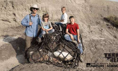A juvenile T. rex dinosaur plays in a natural setting, showcasing it's youthful energy and curiosity.