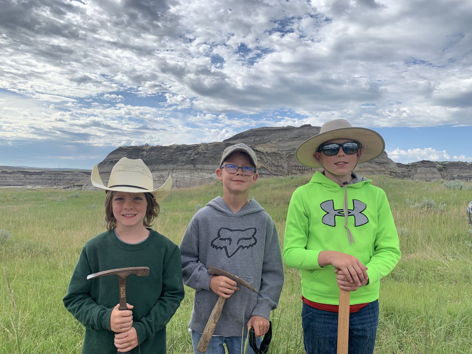 Liam Fisher, Kaiden Madsen, and Jessin Fisher in front of the hill where they discovered their teenage T. rex skeleton in the Badlands of North Dakota. (Photo/Tyler Lyson)