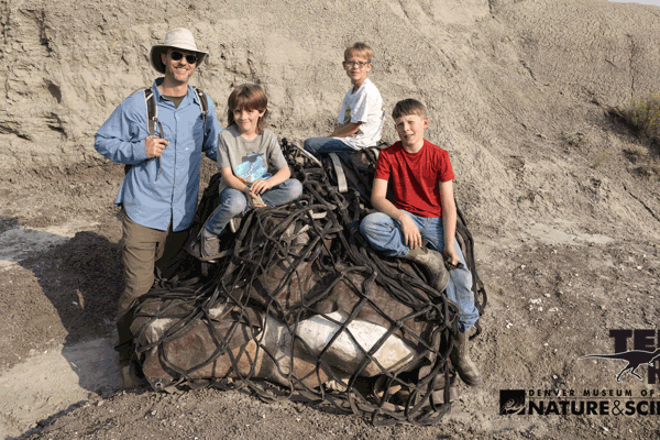 A juvenile T. rex dinosaur plays in a natural setting, showcasing it's youthful energy and curiosity.