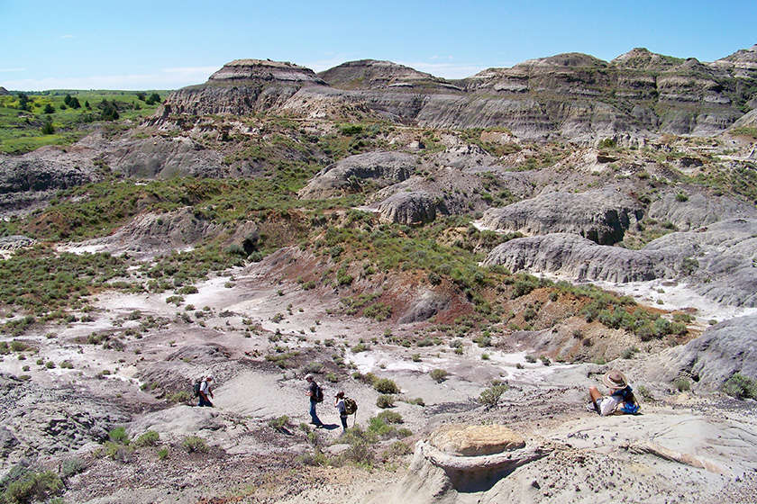 A wide image shot of the Hell Creek area with a couple of people walking in the foreground.
