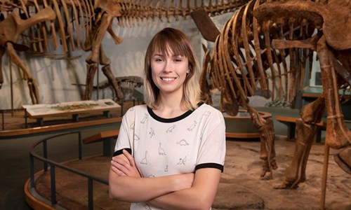 Sadie poses in front of the dinosaurs in Prehistoric Journey