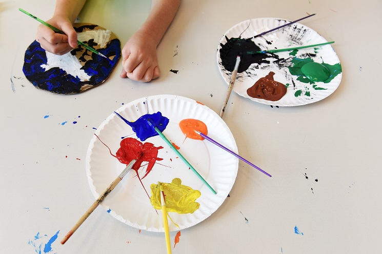 Paper plates with paint and brushes, with children's hands 