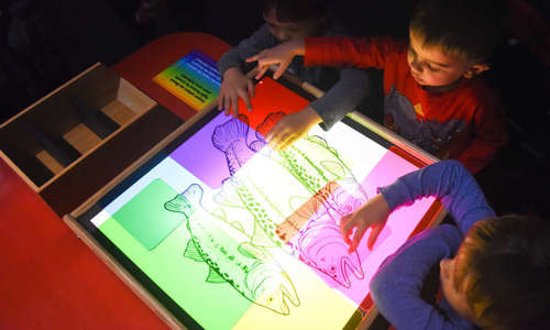 A child plays with a light table and color transparencies.