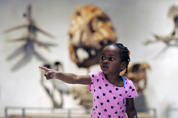 Guest smiling in front of the Stegosaurus display in Prehistoric Journey