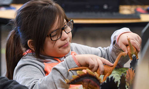 A child plays with plastic dinosaurs