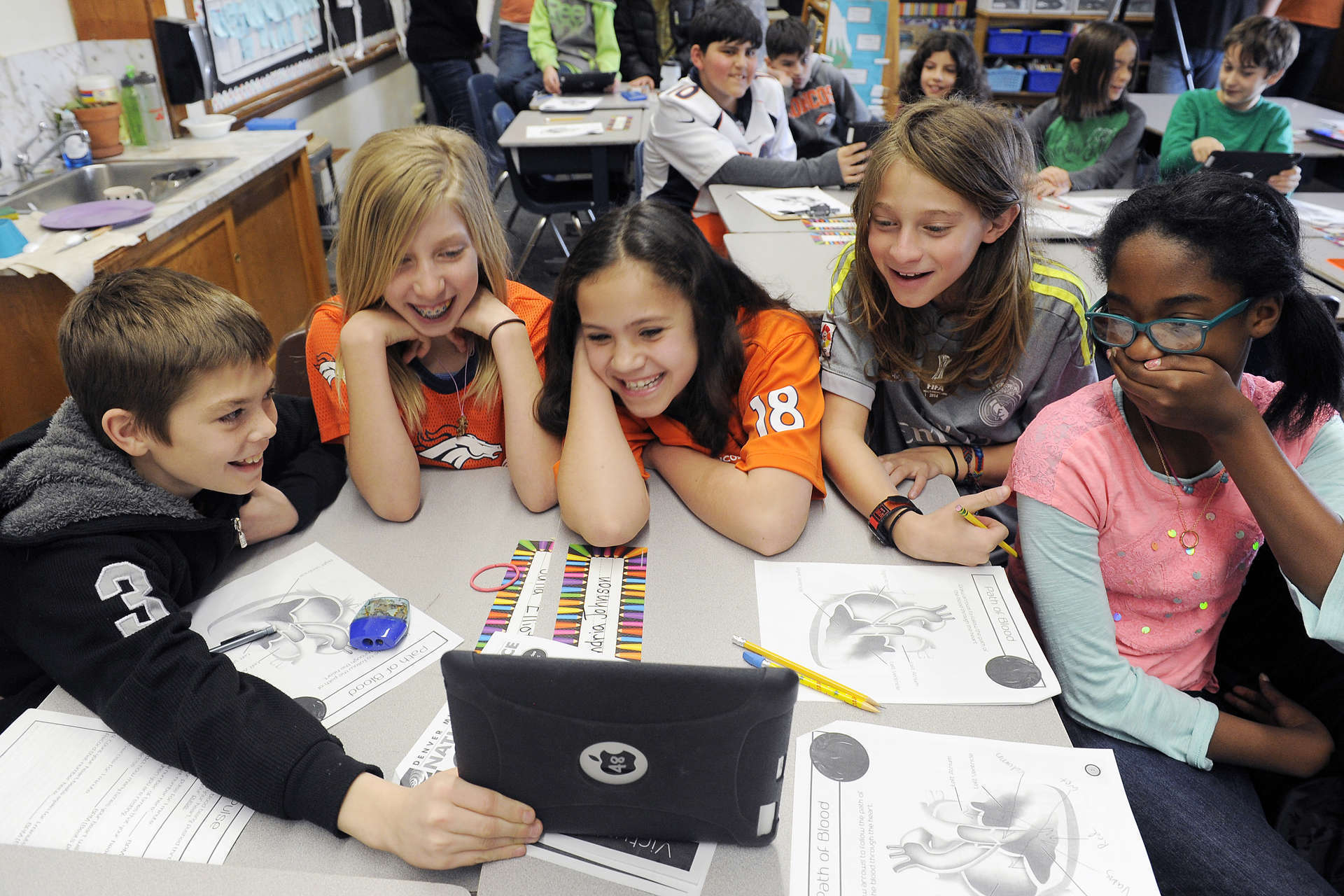 Students group around a tablet as they watch a live dissection with our "Virtual Heart" class.
