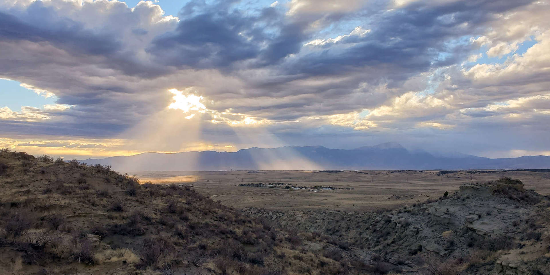 Panaromic view of a partly cloudy sky with sun beaming through, from Corral Bluffs looking west.