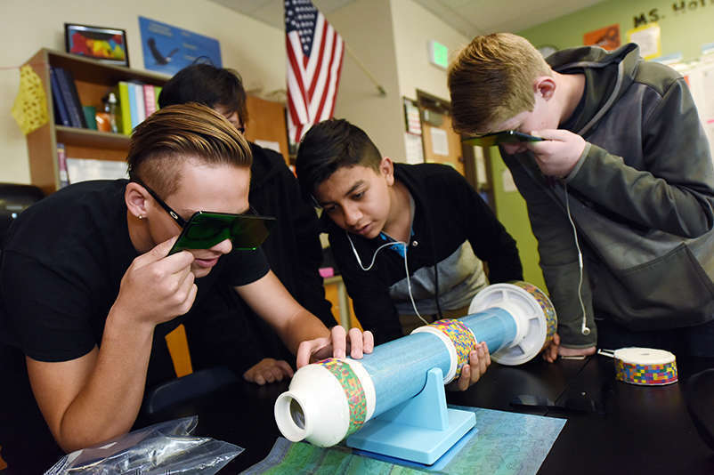 Young adults gather around a tube shaped object