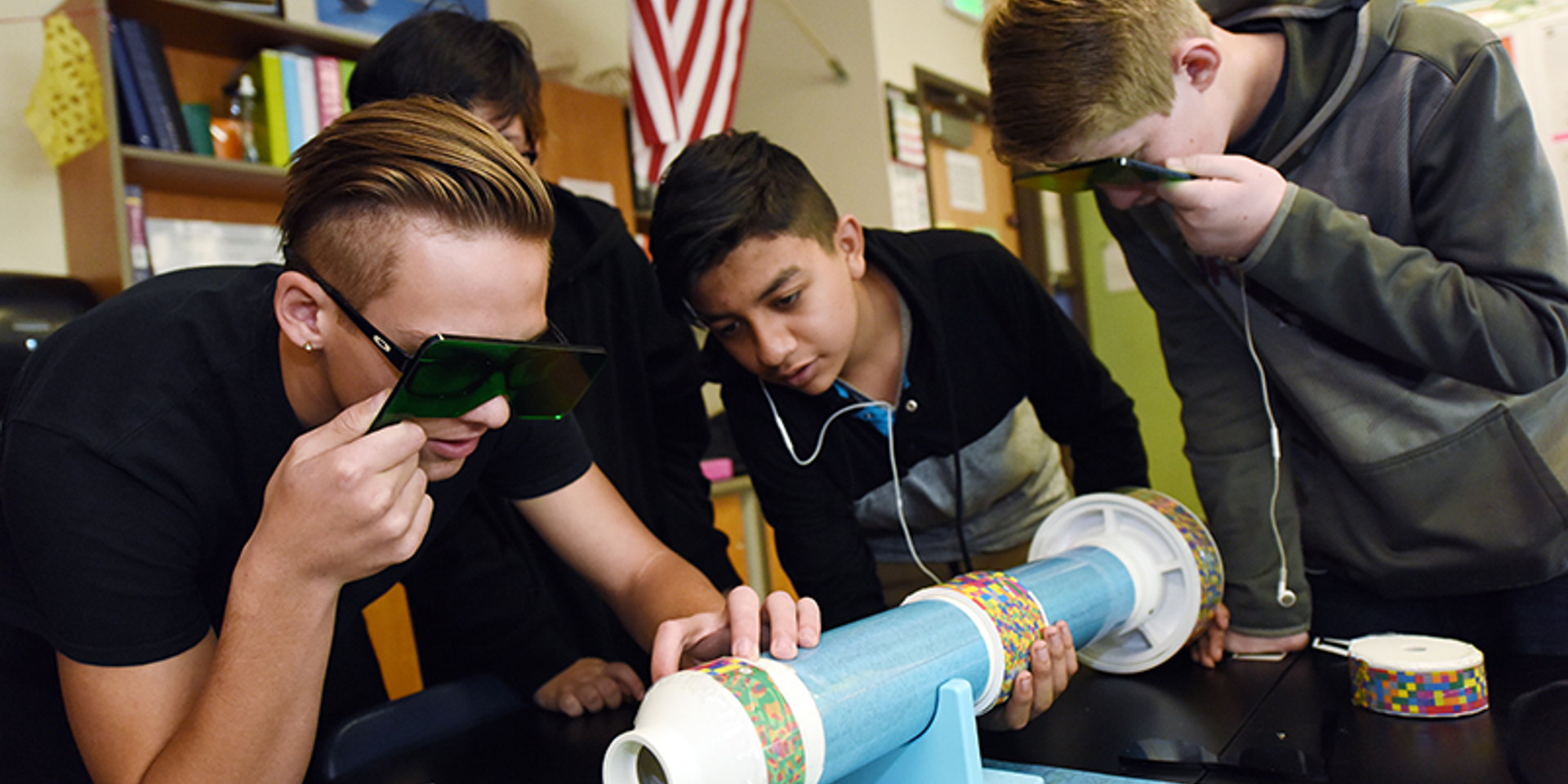 Young adults gather around a tube shaped object