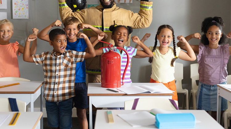 Students and a fire fighter in the classroom, showing "strong arms"